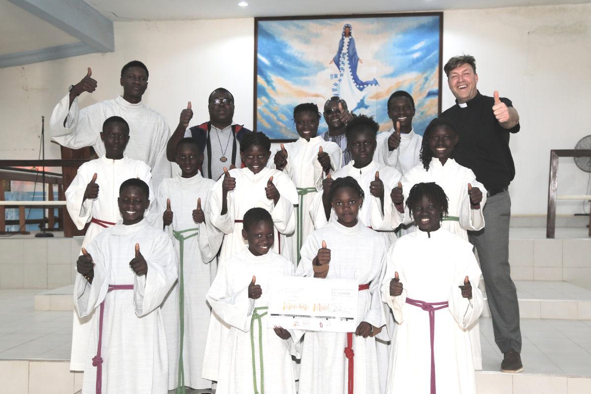 Freuen sich über den Erfolg der Aktion „Minis helfen Minis“: Diözesanjugendpfarrer Gerd Richard Neumeier (oben rechts), sein Kollege Abbé Etienne Mbengue (oben, zweiter von links) und die Ministrant*innen aus Mont Rolland mit den aus der Erzdiözese Bamberg gespendeten Minigewändern.