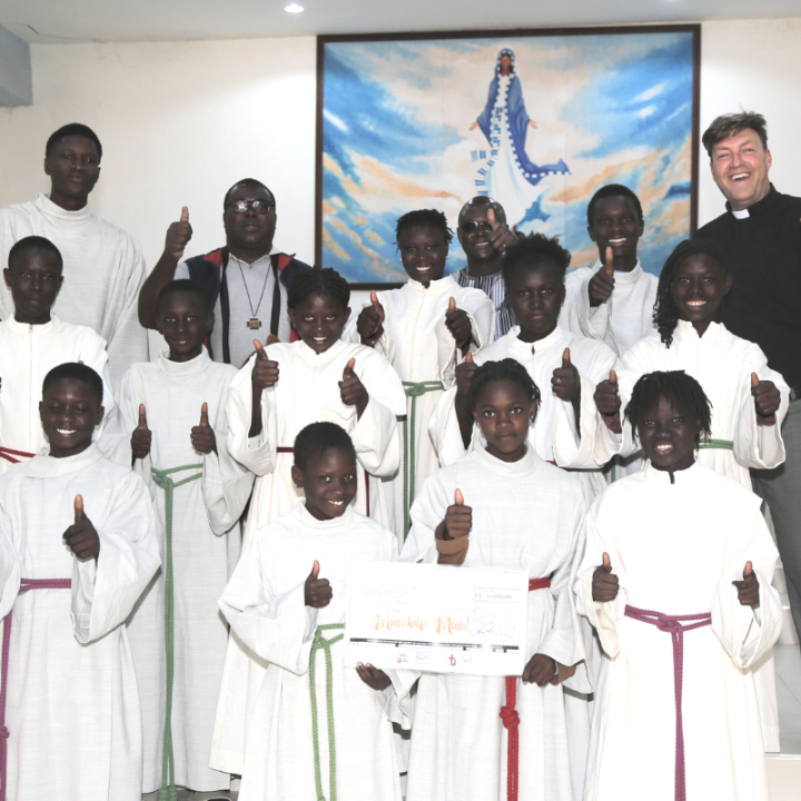 Freuen sich über den Erfolg der Aktion „Minis helfen Minis“: Diözesanjugendpfarrer Gerd Richard Neumeier (oben rechts), sein Kollege Abbé Etienne Mbengue (oben, zweiter von links) und die Ministrant*innen aus Mont Rolland mit den aus der Erzdiözese Bamberg gespendeten Minigewändern.