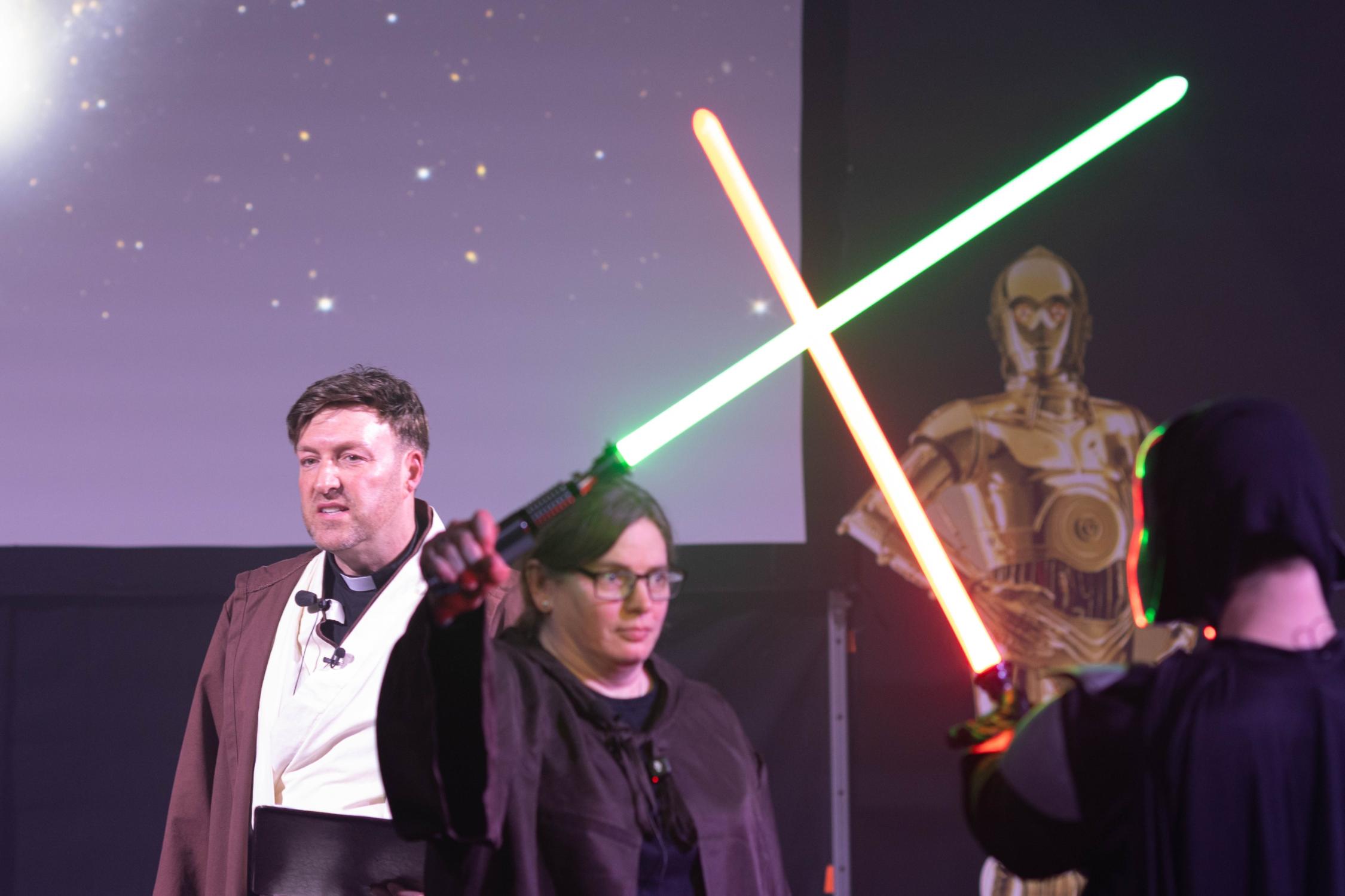 Jugendpfarrer Gerd Richard Neumeier und Anja Baumer-Löw, die mit Darth Vader Lichtschwerter kreuzt