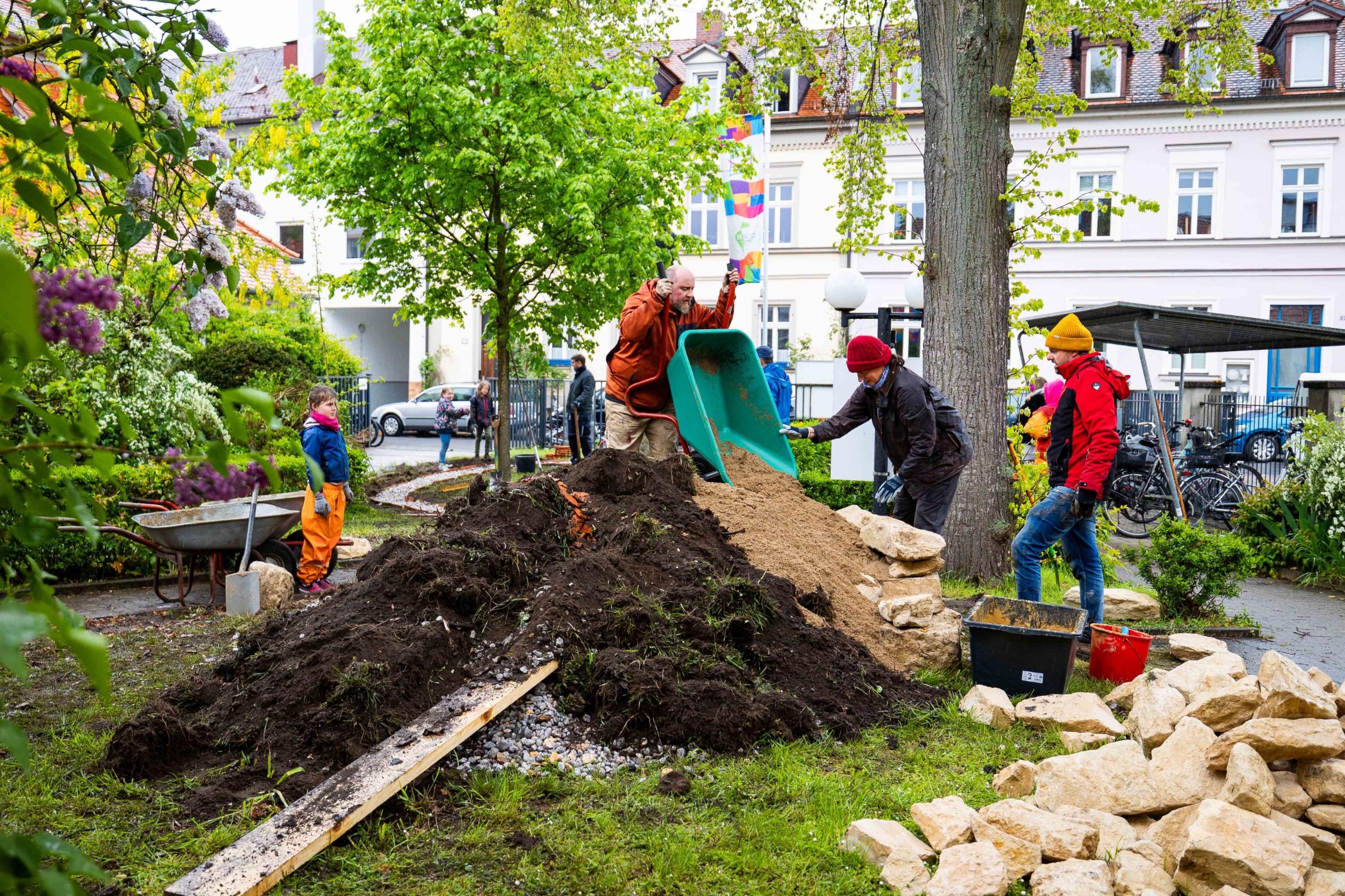 EJA-Mitarbeitende und Kinder arbeiten zusammen im Garten.