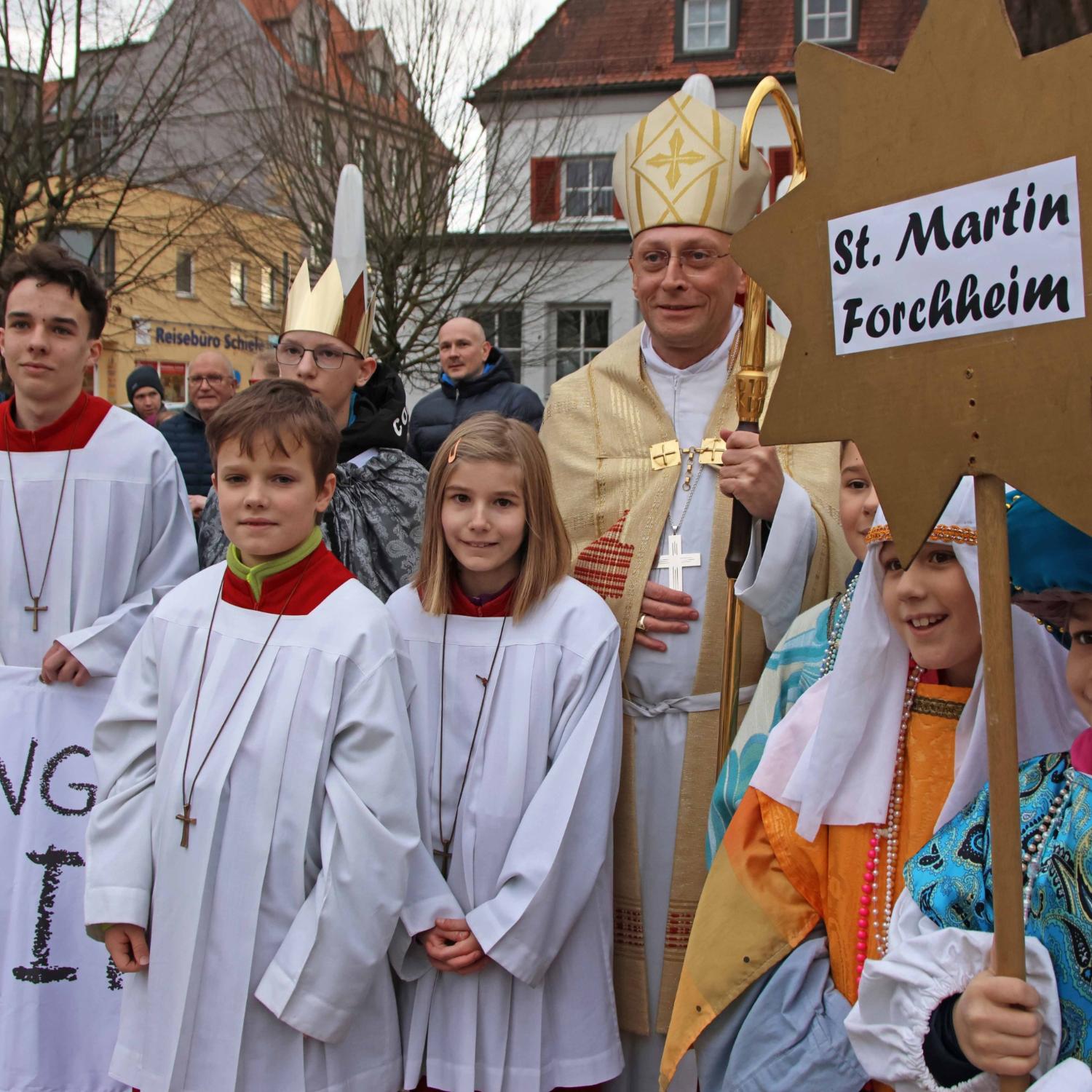 Eine Sternsinger-Gruppe mit Weihbischof Herwig Gössl auf dem Marktplatz in Forchheim.