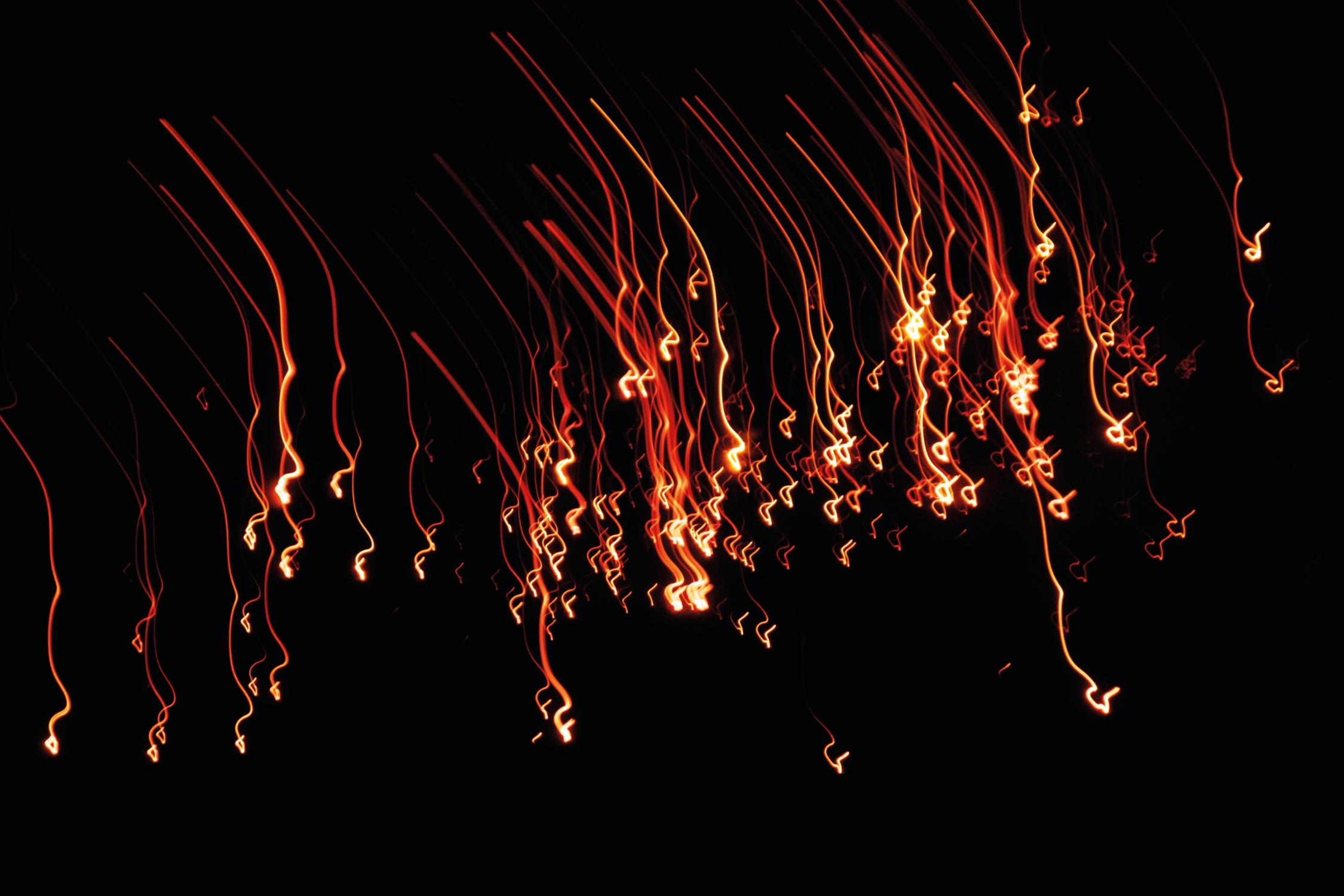 Lichtmalerei mit Funkenflug und feurigen Funken in der Nacht als schwarzem Hintergrund zaubert Leuchtfeuer und Feuerwerk in die Silvesternacht und Silvesterparty
