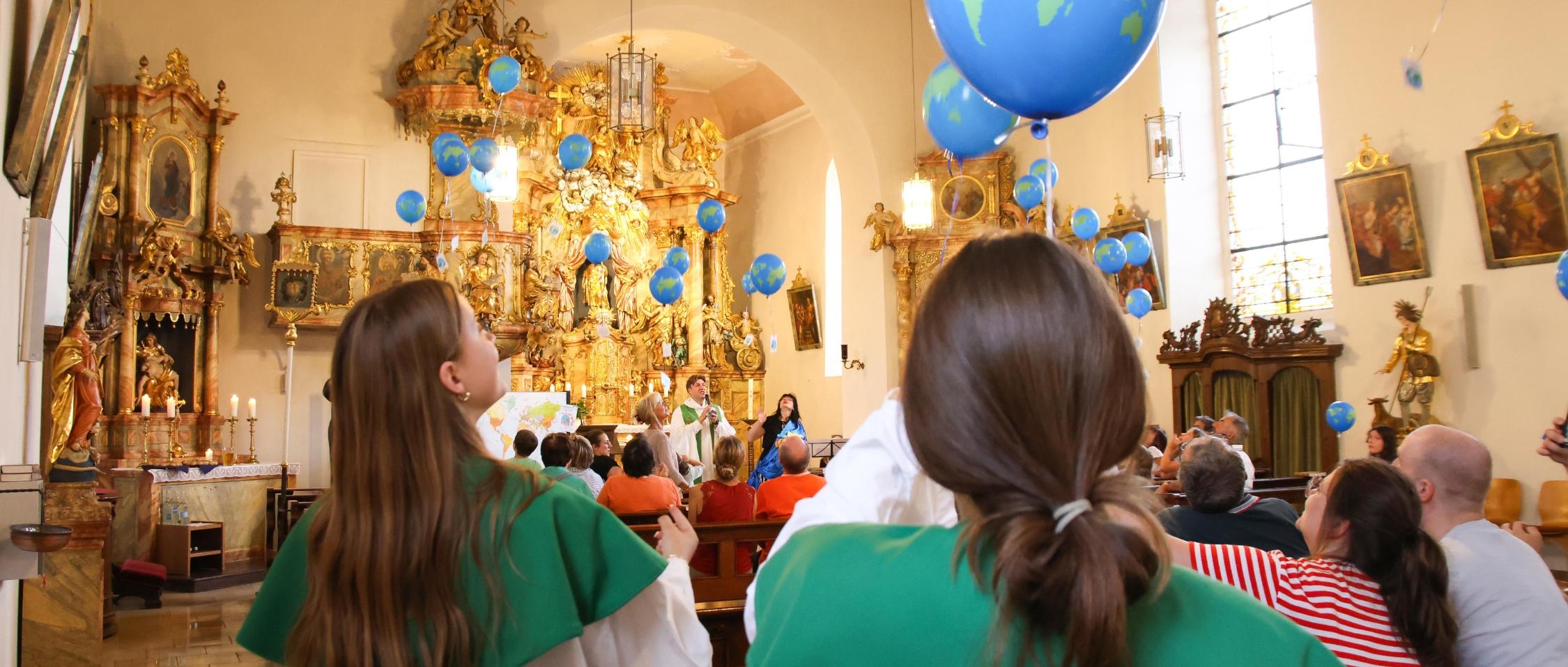 Luftballons steigen zur Kirchendecke hinauf.